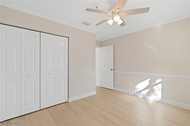 unfurnished bedroom featuring ceiling fan, crown molding, light hardwood / wood-style flooring, and a closet