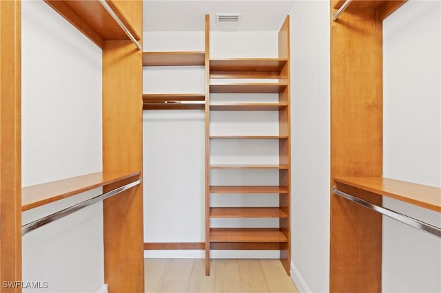 walk in closet with light hardwood / wood-style floors