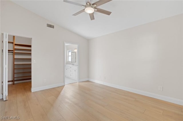 unfurnished bedroom with ceiling fan, light hardwood / wood-style flooring, a spacious closet, connected bathroom, and lofted ceiling