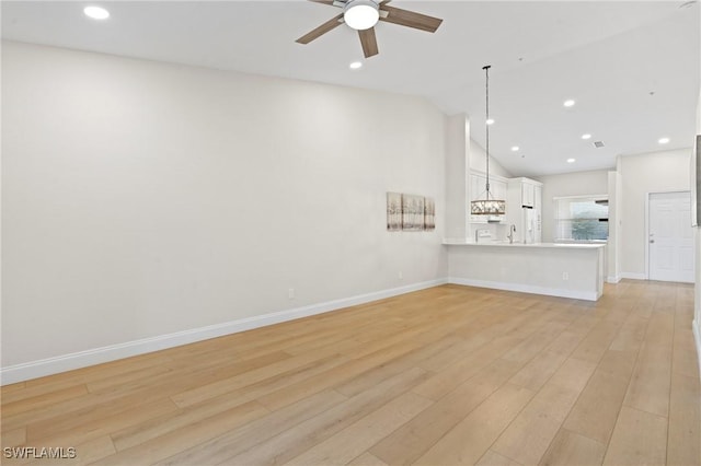 unfurnished living room featuring light wood-type flooring, vaulted ceiling, and ceiling fan