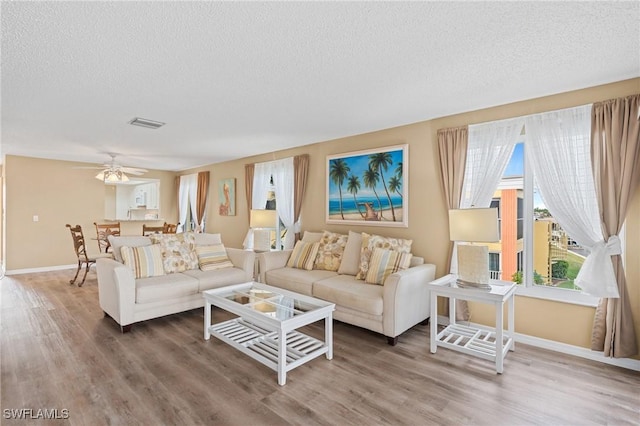 living room featuring hardwood / wood-style floors, ceiling fan, and a textured ceiling