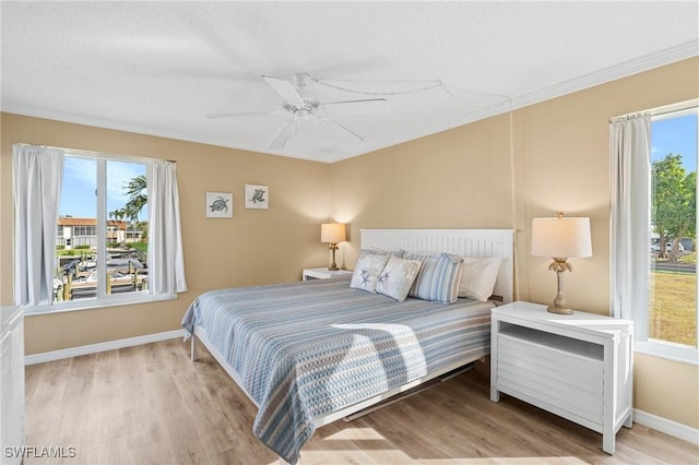 bedroom with multiple windows, ceiling fan, and light wood-type flooring