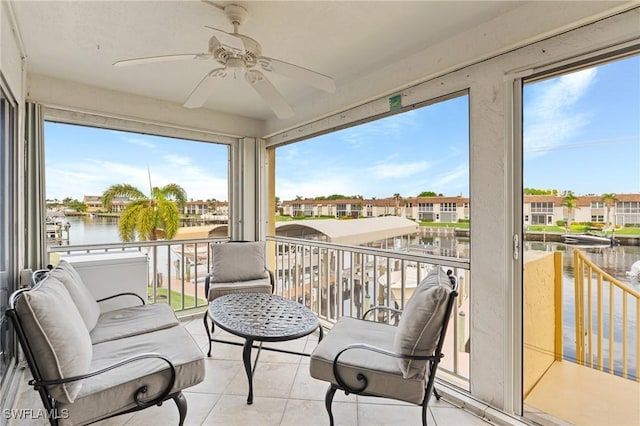 sunroom featuring ceiling fan and a water view