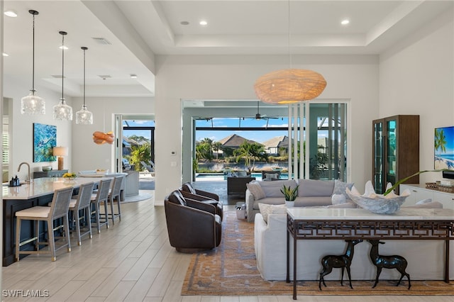 living room featuring a tray ceiling and sink