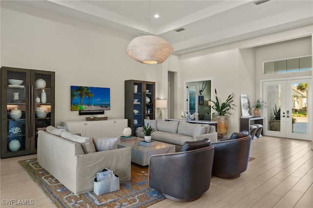 living room featuring french doors, a towering ceiling, and light hardwood / wood-style flooring