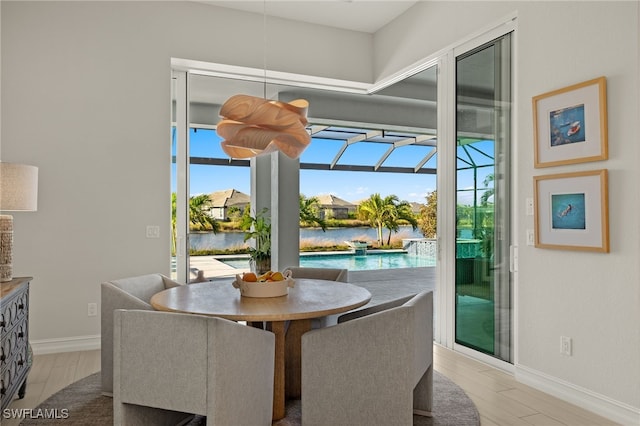 dining area with light wood-type flooring and a water view