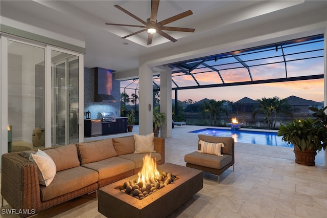 patio terrace at dusk with a lanai, grilling area, and an outdoor living space with a fire pit