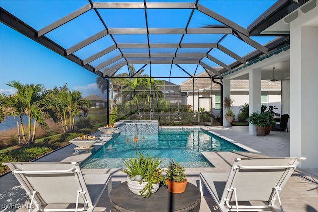 view of swimming pool with glass enclosure, ceiling fan, an in ground hot tub, and a patio