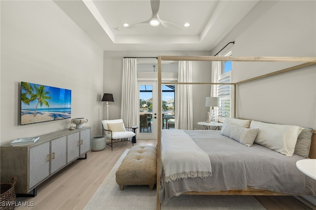 bedroom featuring ceiling fan, a tray ceiling, access to outside, and light hardwood / wood-style flooring