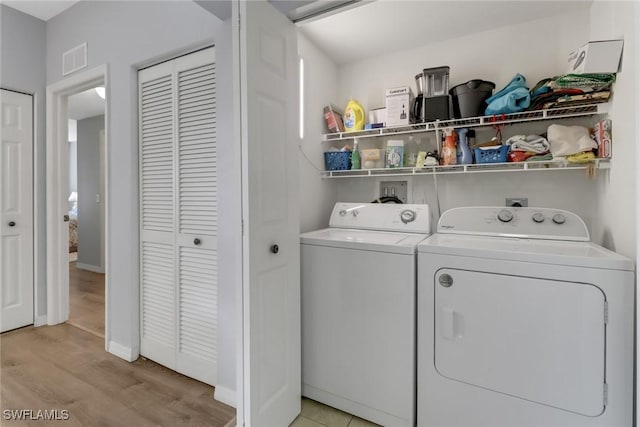 laundry area with washer and dryer and light hardwood / wood-style flooring