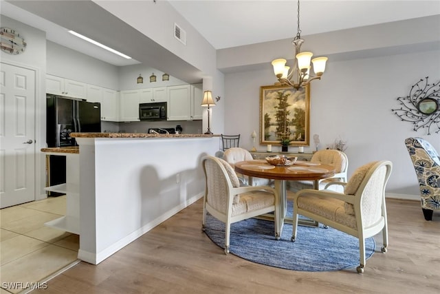 dining space featuring light hardwood / wood-style floors and a chandelier