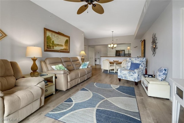 living room with ceiling fan with notable chandelier and hardwood / wood-style flooring