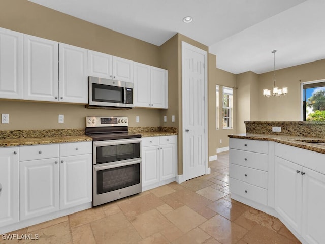 kitchen with dark stone countertops, white cabinets, stainless steel appliances, and decorative light fixtures