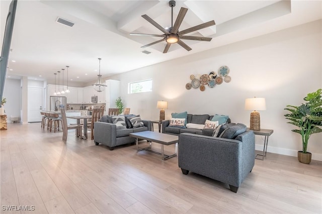 living room featuring ceiling fan with notable chandelier and light wood-type flooring