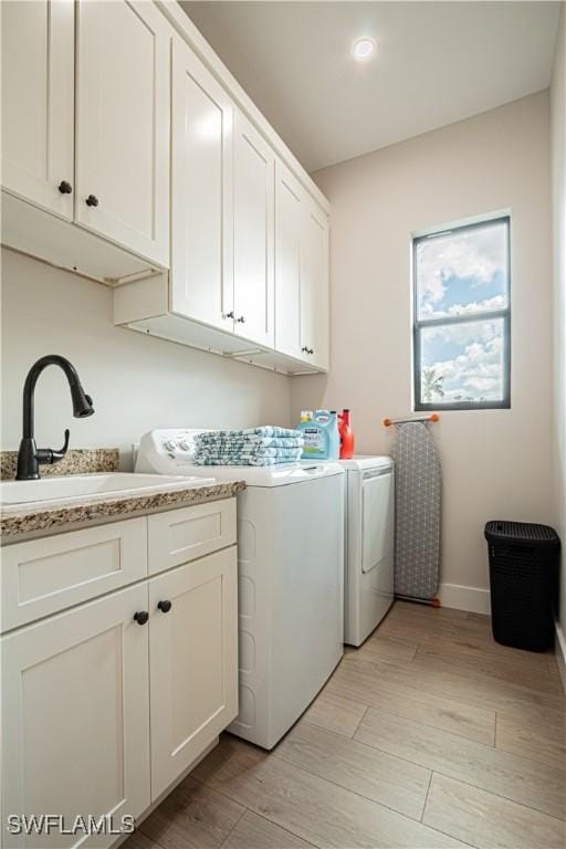 laundry area featuring cabinets, washing machine and dryer, and sink