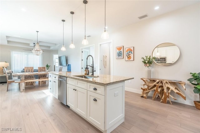 kitchen featuring light stone countertops, sink, stainless steel dishwasher, a kitchen island with sink, and white cabinets