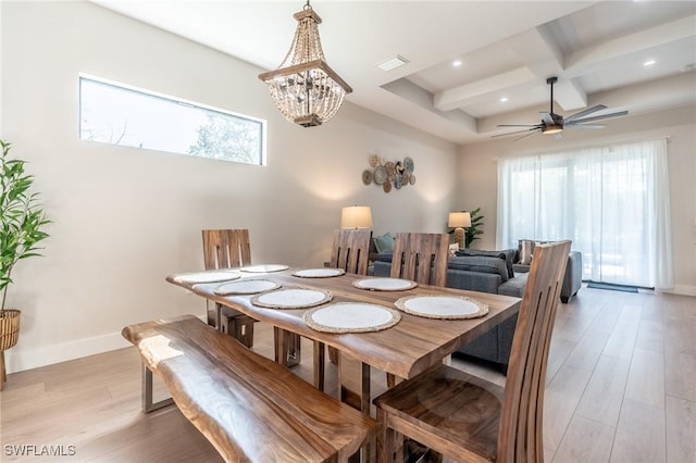 dining room with ceiling fan with notable chandelier, light hardwood / wood-style flooring, a wealth of natural light, and coffered ceiling