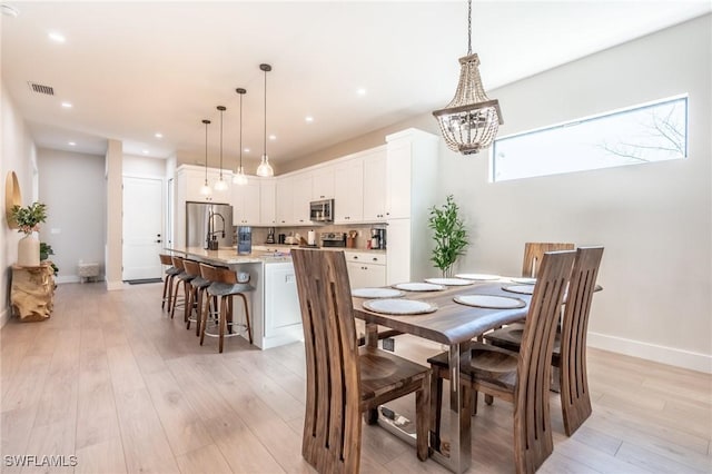 dining area featuring a notable chandelier and light wood-type flooring