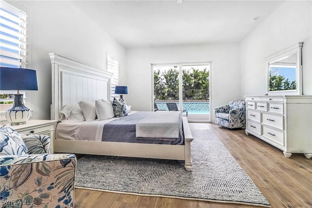 bedroom with access to outside, multiple windows, and wood finished floors