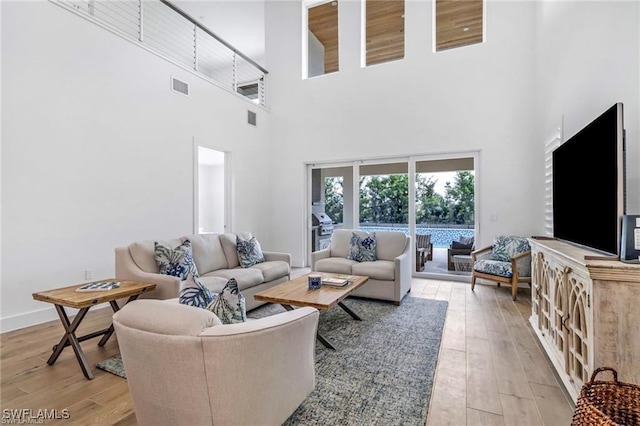 living room featuring light wood-style flooring, visible vents, and baseboards