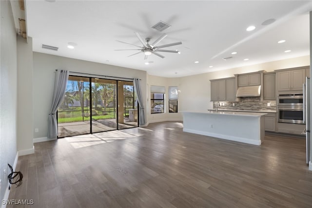 kitchen featuring a kitchen island with sink, gray cabinets, tasteful backsplash, dark hardwood / wood-style flooring, and stainless steel double oven