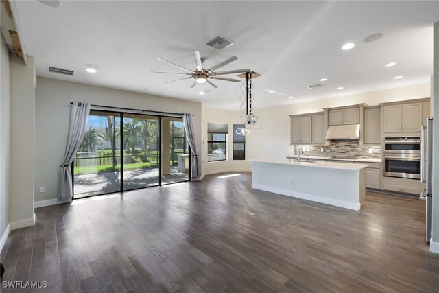 kitchen with decorative backsplash, appliances with stainless steel finishes, dark hardwood / wood-style flooring, a kitchen island with sink, and sink