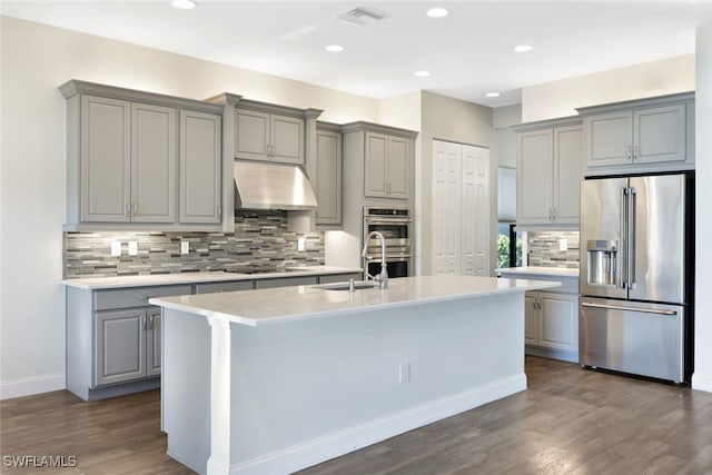 kitchen featuring a kitchen island with sink, dark wood-type flooring, sink, gray cabinets, and appliances with stainless steel finishes