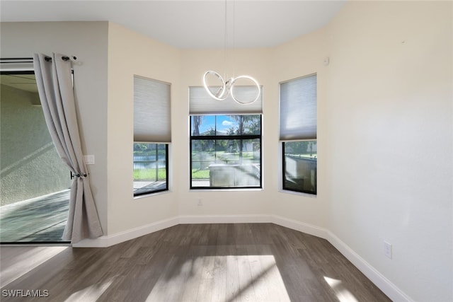 unfurnished dining area with dark wood-type flooring and a notable chandelier