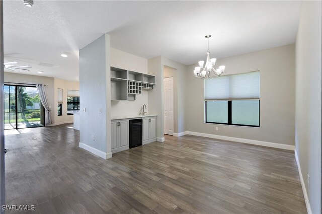 kitchen featuring sink, hanging light fixtures, wine cooler, dark hardwood / wood-style floors, and ceiling fan with notable chandelier