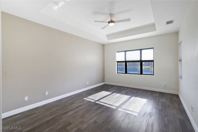 spare room with dark hardwood / wood-style floors, ceiling fan, and a tray ceiling