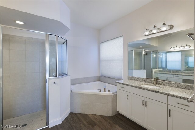 bathroom featuring vanity, wood-type flooring, and plus walk in shower