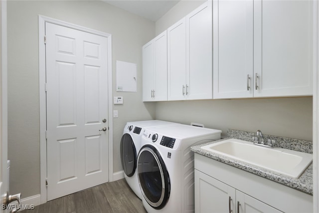 laundry room featuring washer and clothes dryer, dark hardwood / wood-style floors, cabinets, and sink