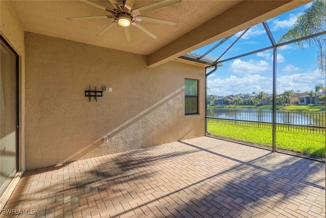 unfurnished sunroom featuring beamed ceiling, ceiling fan, and a water view