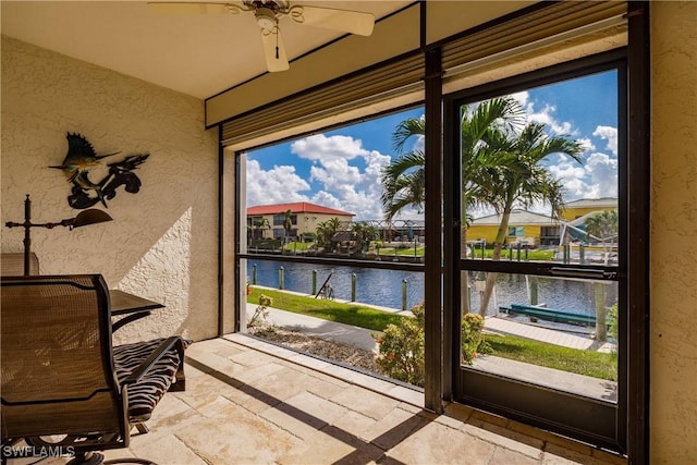 doorway with a water view, plenty of natural light, and ceiling fan