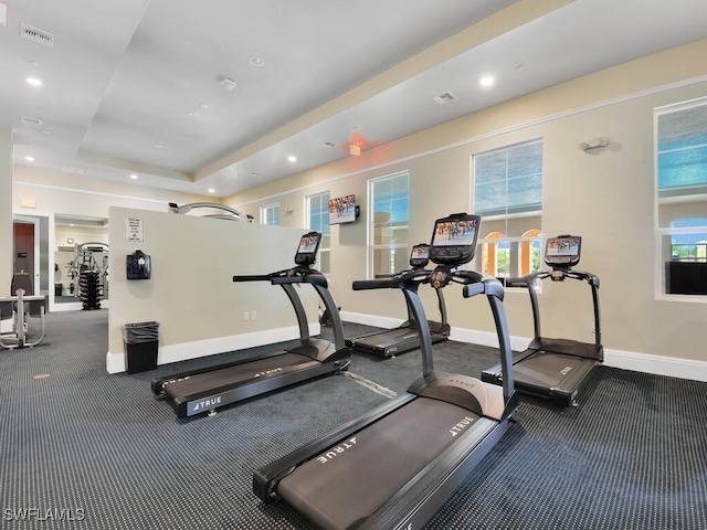 workout area with a tray ceiling