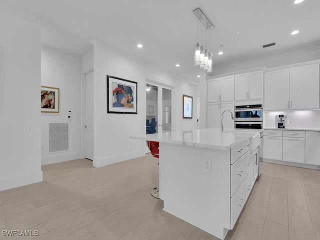 kitchen with backsplash, crown molding, an island with sink, pendant lighting, and white cabinets