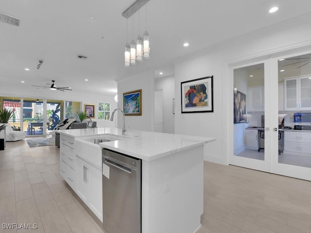 kitchen with ceiling fan, stainless steel dishwasher, pendant lighting, a kitchen island with sink, and white cabinets