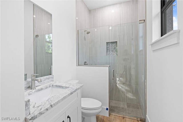 bathroom featuring hardwood / wood-style flooring, vanity, toilet, and a shower with shower door