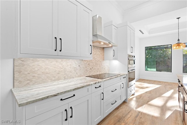 kitchen featuring white cabinetry, black electric cooktop, decorative backsplash, and wall chimney range hood