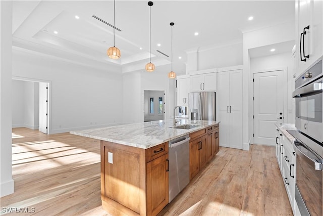 kitchen with appliances with stainless steel finishes, a spacious island, sink, pendant lighting, and white cabinets