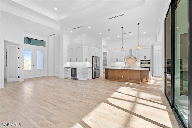 kitchen featuring pendant lighting, backsplash, white cabinets, a spacious island, and stainless steel fridge with ice dispenser