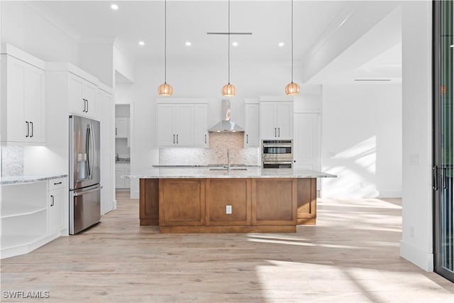 kitchen featuring white cabinets, pendant lighting, wall chimney range hood, and appliances with stainless steel finishes