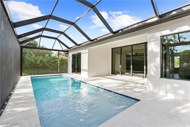 view of swimming pool with glass enclosure and a patio