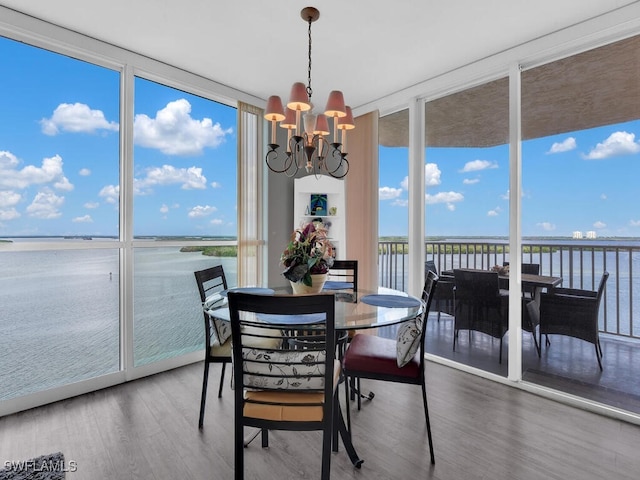 dining room featuring a water view, a wall of windows, wood-type flooring, and a chandelier