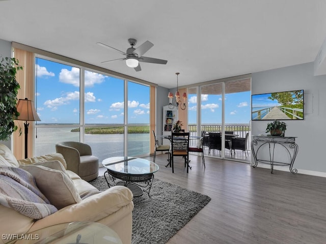 living room with wood-type flooring, ceiling fan with notable chandelier, a water view, and expansive windows