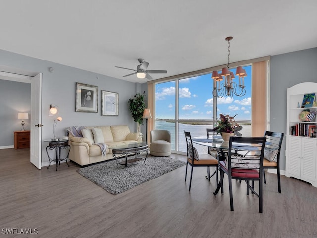 living room with hardwood / wood-style flooring, ceiling fan with notable chandelier, expansive windows, and a water view