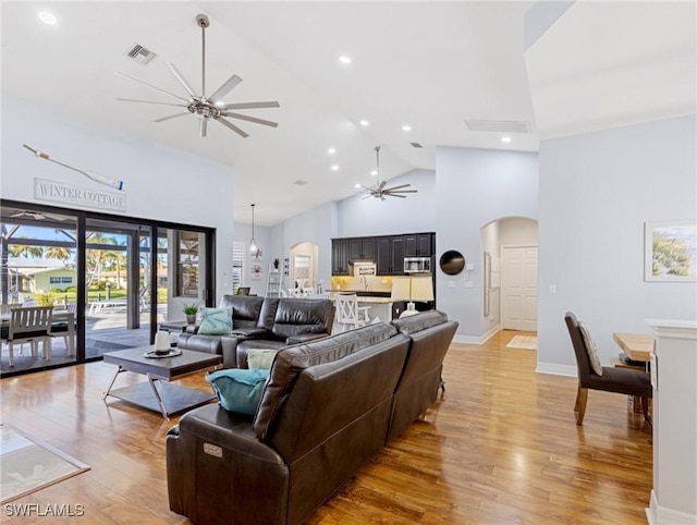 living room with ceiling fan, high vaulted ceiling, and light hardwood / wood-style floors