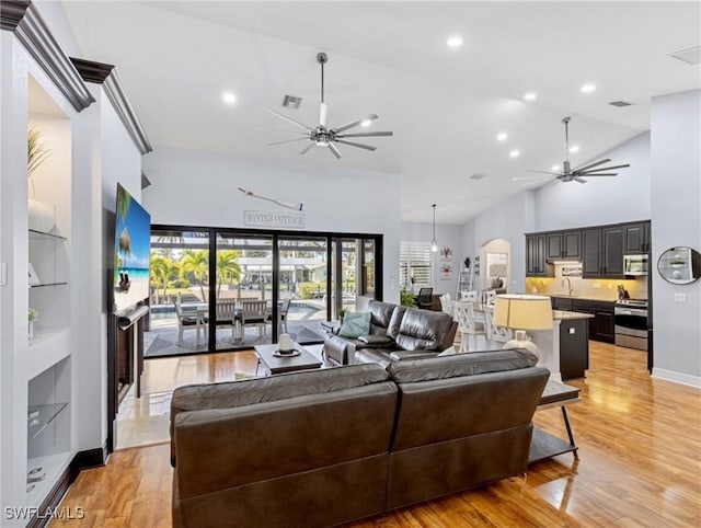 living room with ceiling fan, sink, high vaulted ceiling, and light hardwood / wood-style flooring