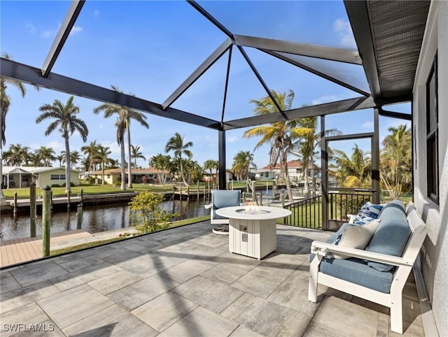 view of patio featuring a lanai, a dock, a water view, and an outdoor fire pit