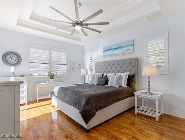 bedroom featuring wood-type flooring, a raised ceiling, ceiling fan, and crown molding